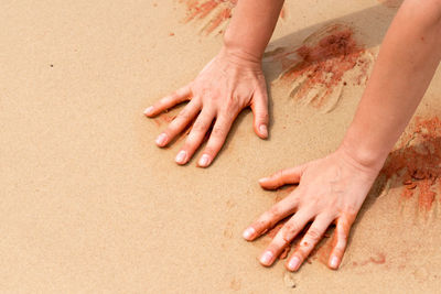 Cropped image of hands on sand at beach