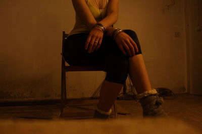 Low section of woman sitting on chair at home
