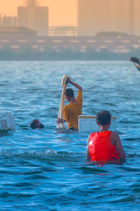 Rear view of people in swimming pool against sea