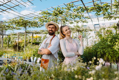 Portrait of colleagues in garden centre. garden workers in aprons are looking at camera.