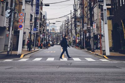 Side view of man crossing road in city