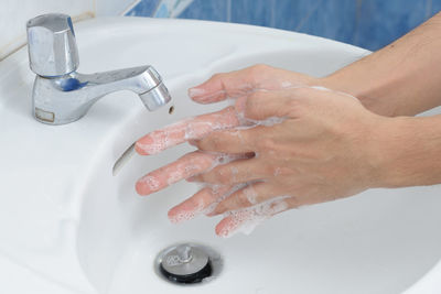 Cropped image of man washing hands in sink