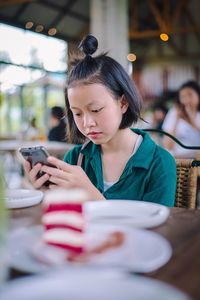 Teenage girl using phone at cafe