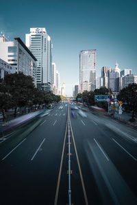 Blurred motion of vehicles on road in city against blue sky