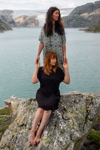 Young woman standing on rock by sea