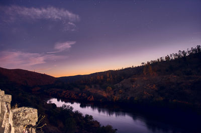 Scenic view of lake and mountains against sky at night