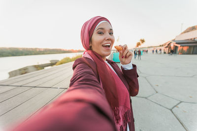 Portrait of young woman standing against sky