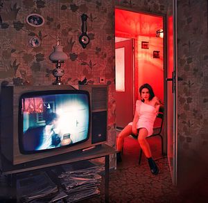 Portrait of woman wearing dress sitting on chair at home seen through doorway