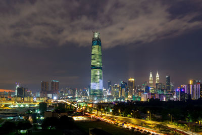 Illuminated modern buildings in city against sky at night