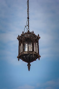 Low angle view of old lantern hanging against sky