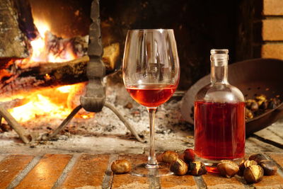 Close-up of red wine and chestnuts by fireplace at home