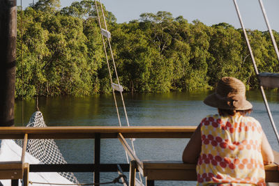 Rear view of female tourist on a cruise ship looking towards the mangrove forest