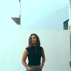 Young woman standing against wall