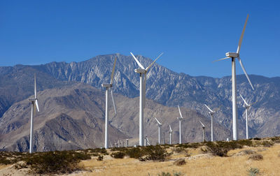 Windmill by mountains against blue sky