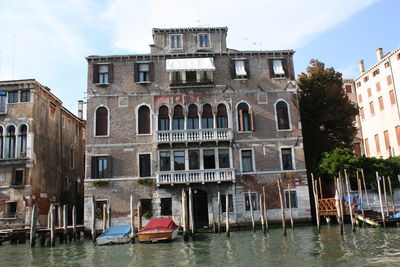 Boats in canal by buildings against sky