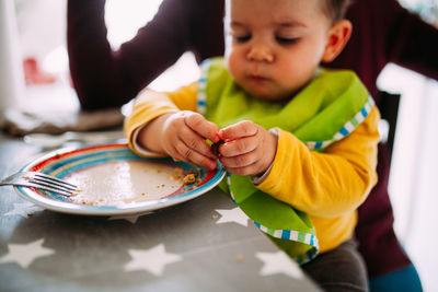 Midsection of boy holding while sitting on table