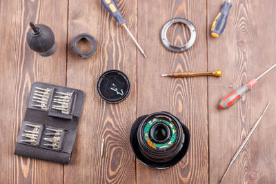 Half-disassembled camera zoom lens on wooden table surrounded with tools