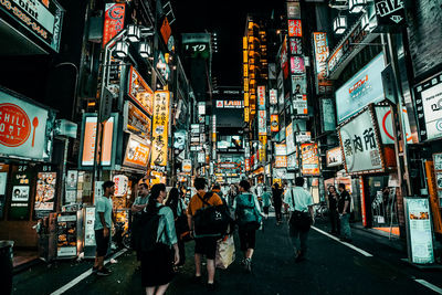 People on illuminated street in city at night