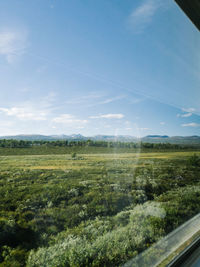 Scenic view of field against sky through train window