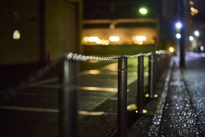 Illuminated railing by street in city at night