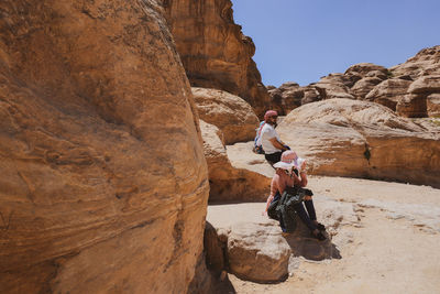 Man standing on rock against sky