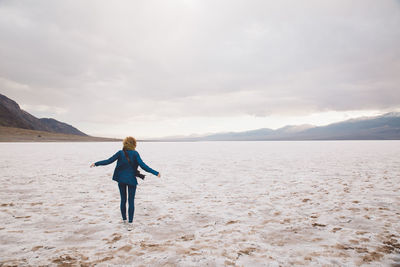 Woman standing on beach against sky