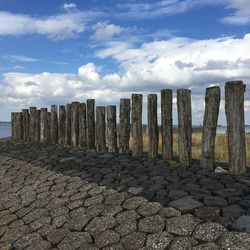 Wooden posts on fence against sky