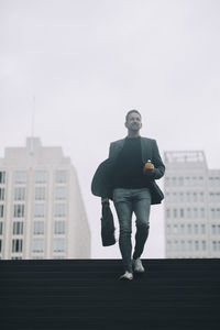 Businessman moving on steps at subway against clear sky