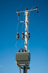 Low angle view of telephone pole against clear blue sky