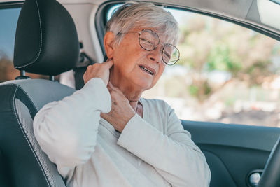 Senior woman wearing eyeglasses sitting in car