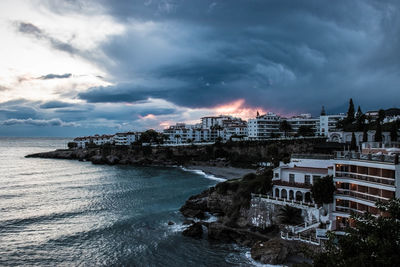 Buildings by sea against sky at dusk