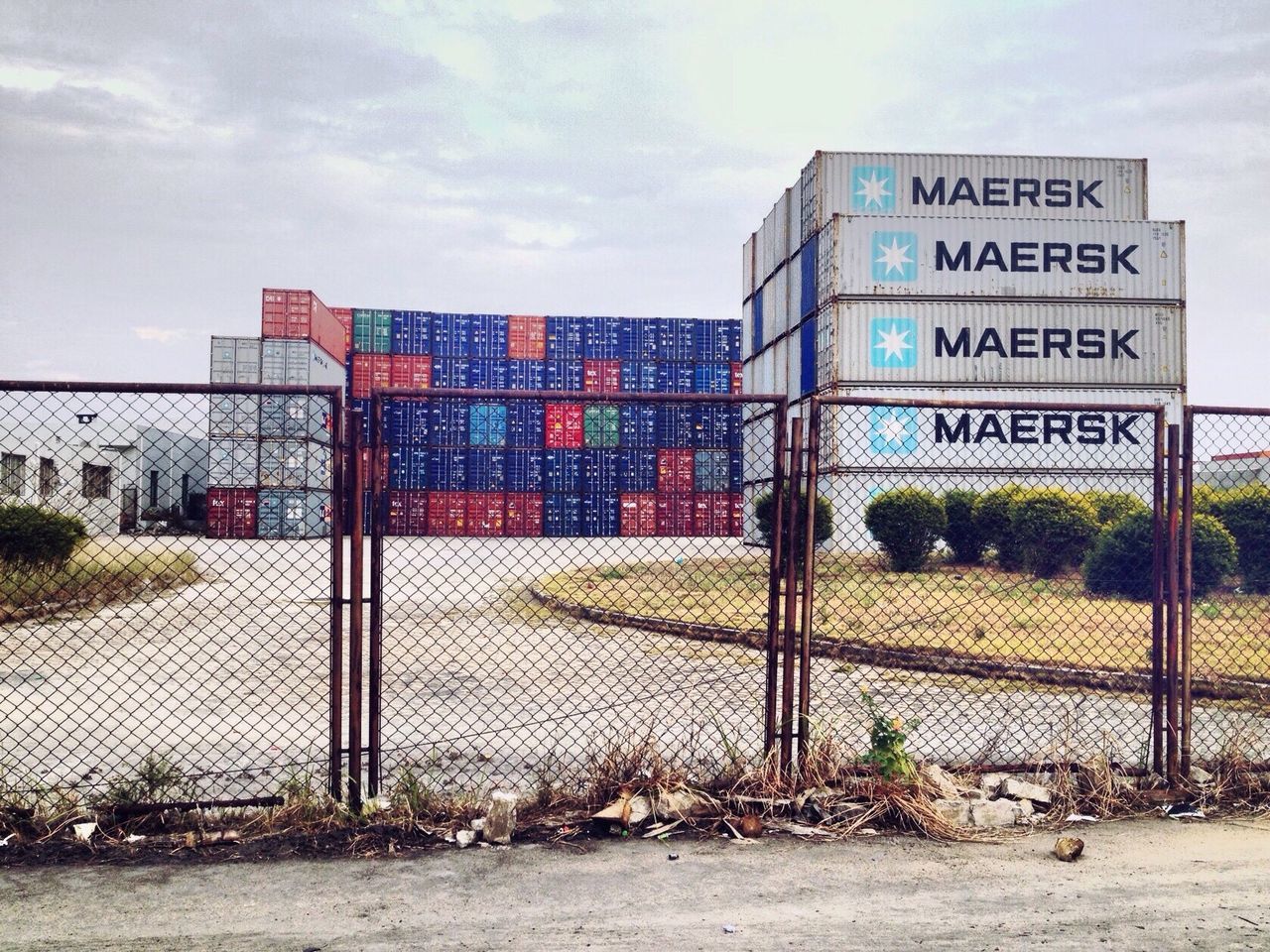 building exterior, architecture, built structure, sky, fence, safety, text, chainlink fence, protection, western script, cloud - sky, day, transportation, metal, security, city, outdoors, communication, road, grass