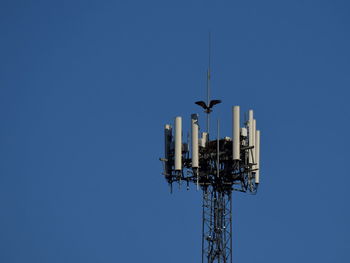 Low angle view of communications tower against clear blue sky