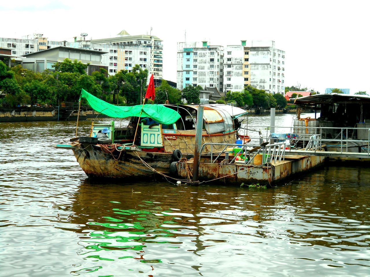 FISHING BOAT IN RIVER BY BUILDINGS IN CITY