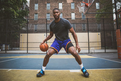Young man practicing basketball in court