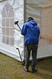 Full length rear view of man making tent on field