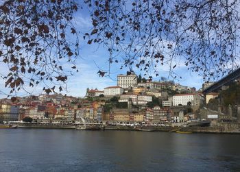 Buildings by river against sky in town