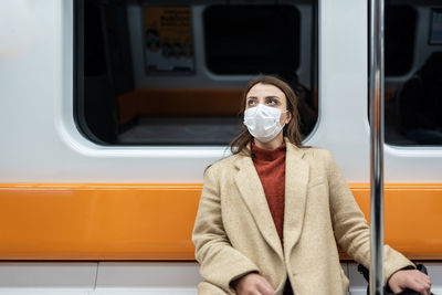 Portrait of woman wearing mask sitting in train