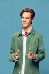 Portrait of young man standing against blue background