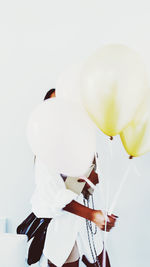 Rear view of men with balloons against white background