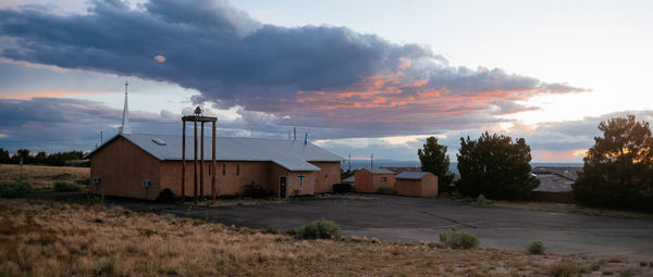 Houses on field against sky during sunset