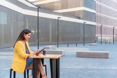 Woman using mobile phone while standing on laptop