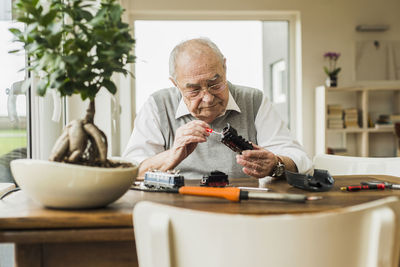 Senior man repairing toy train at home