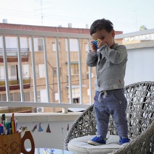 Cute boy standing on chair against railing