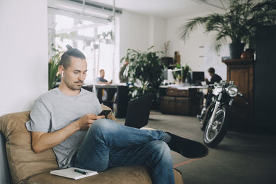 Confident businessman using technologies while sitting in creative office