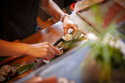 Midsection of man preparing sushi on table