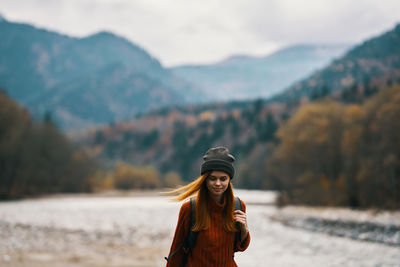 Portrait of smiling young woman standing against mountains