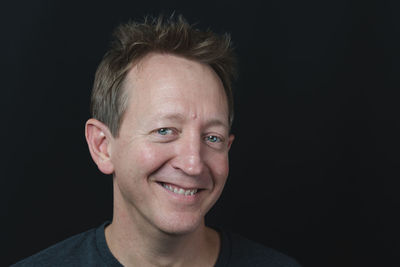 Portrait of smiling man against black background
