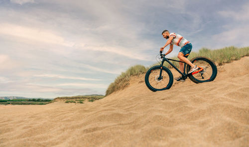 Man riding a fat bike through the beach dunes