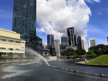 Road by buildings against sky in city